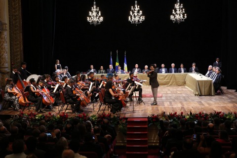 Fotografia de uma orquestra tocando no palco de um teatro